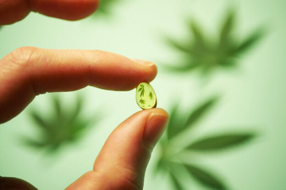 Close-up of a hand holding a CBD oil droplet, symbolizing the benefits of microdosing for balance and wellness.